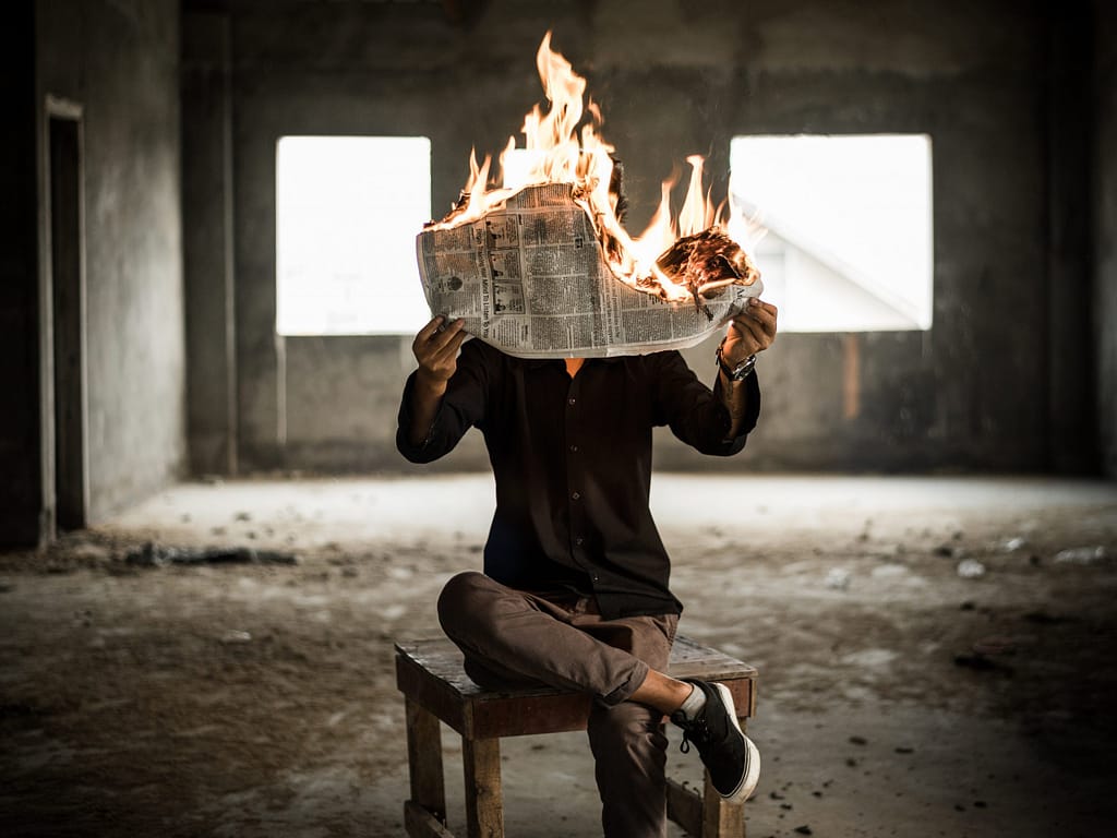 Man reading a news paper while it's burning