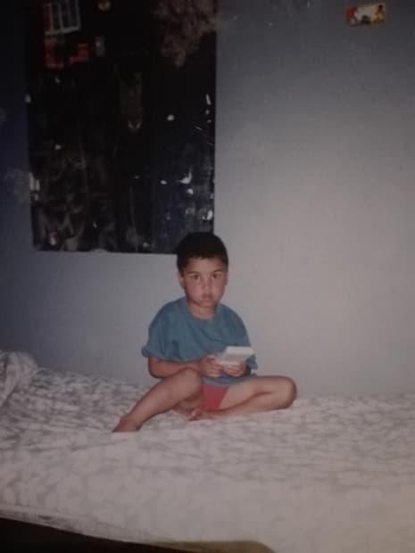 Lucian Van Wyk as a child sitting on a bed