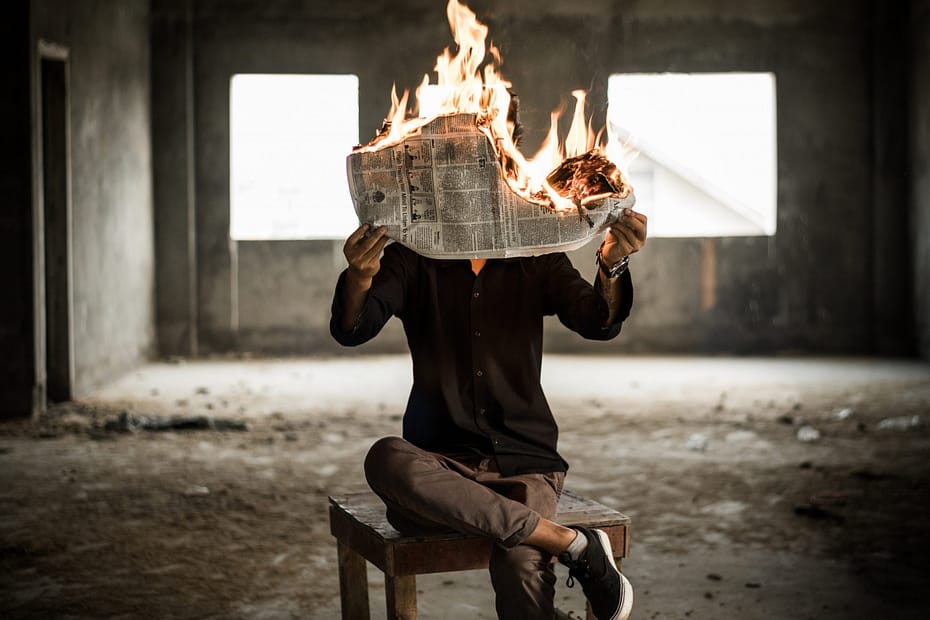 Man reading a news paper while it's burning